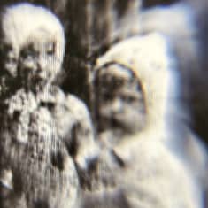 Epäselvä kuva kahdesta lapsihahmosta, valokuva tietokoneruudun läpi vanhasta lasinegatiivista.