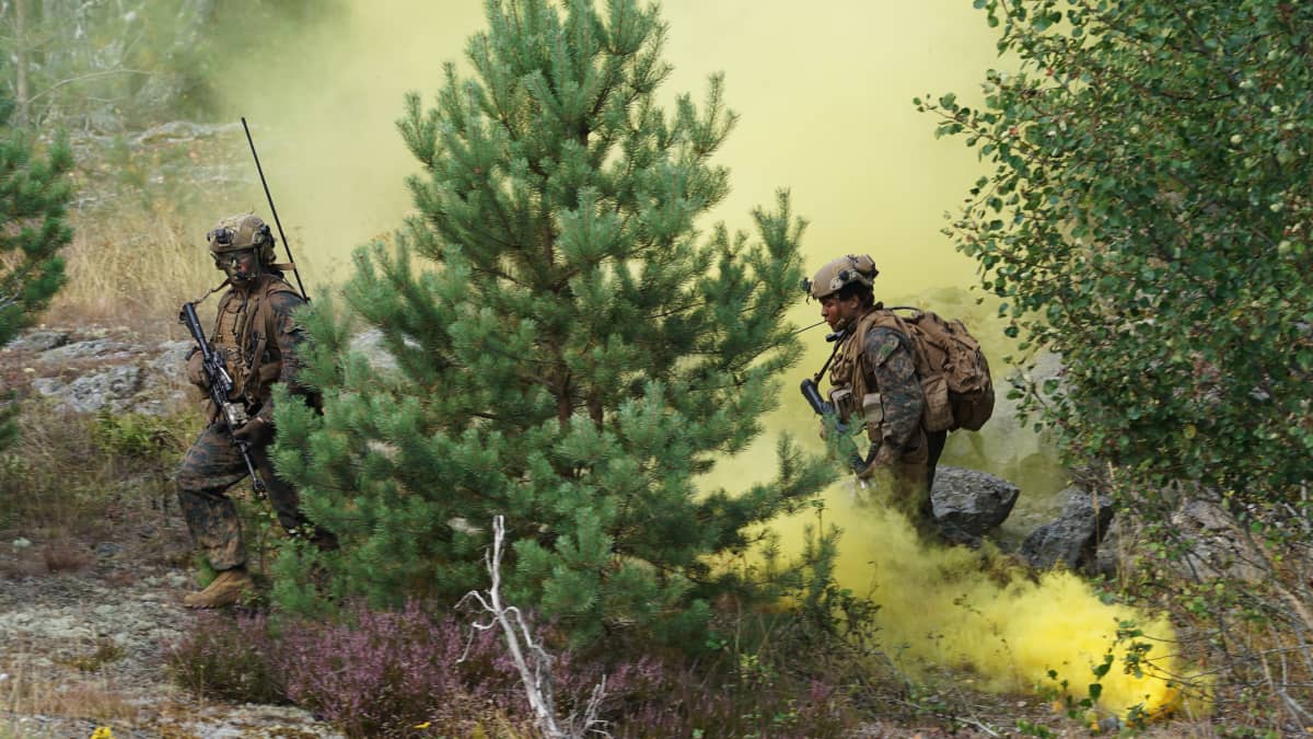 Sotilaat kulkevat harjoituksissa puiden välissä. Ilmaan tupruaa keltaista savua.