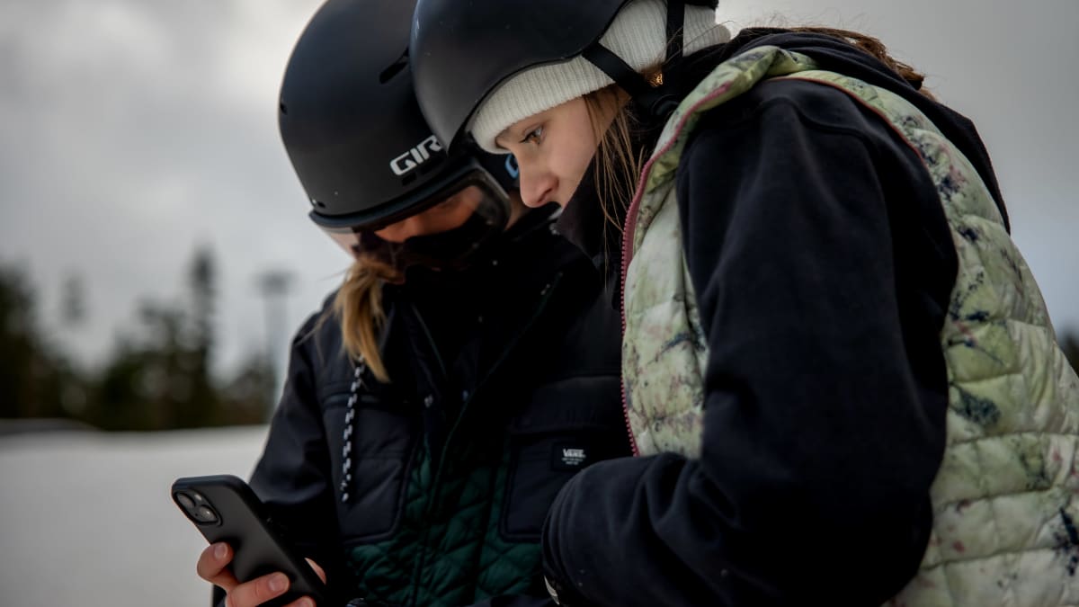  Telma Särkipaju ja Enni Rukajärvi katselevat kuvauksiaan puhelimen näytöltä.