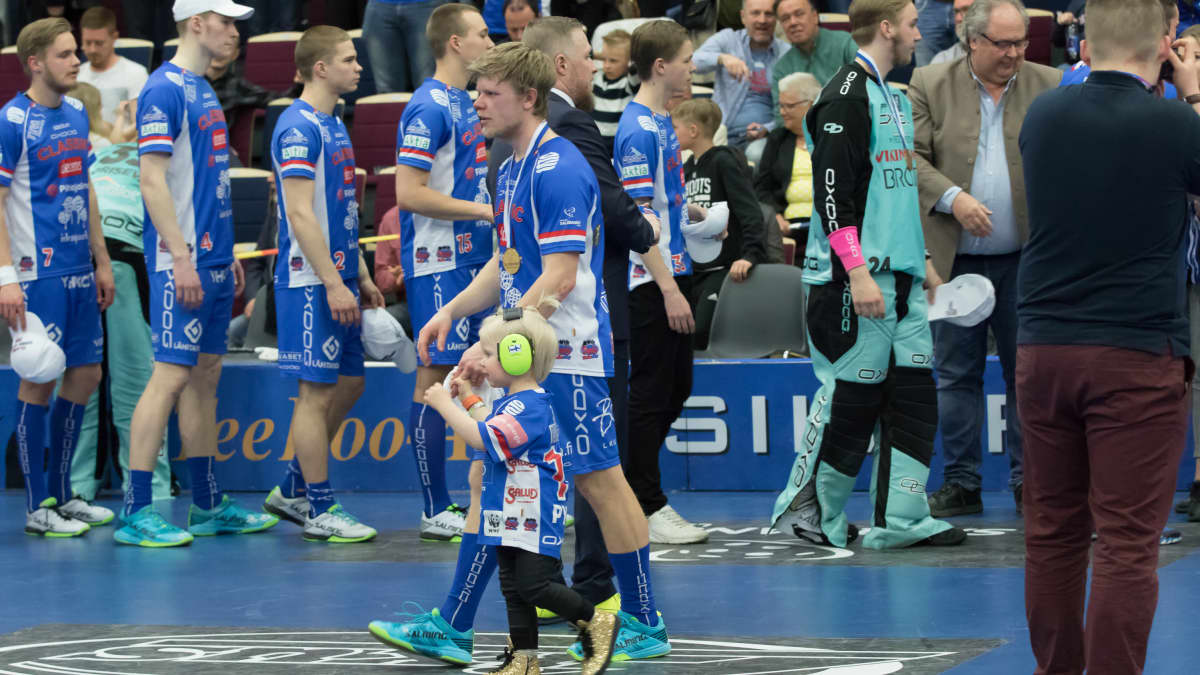 Joonas Pylsy kävelee poikansa kanssa kultamitali kaulassa Classicin ja TPS:n välisen salibandyfinaalin jälkeen huhtikuussa 2019.