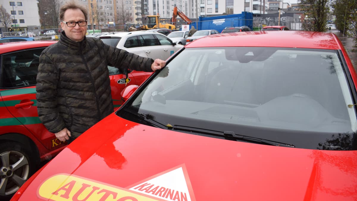 Autokoulun opettaja ja yrittäjä Hemmo Sankari seisoo autonsa vieressä.