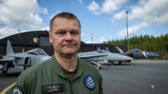 Juha-Pekka Keränen katsoo vakavana kameraan. Taustalla näkyy eri merkkisiä hävittäjälentokoneita.