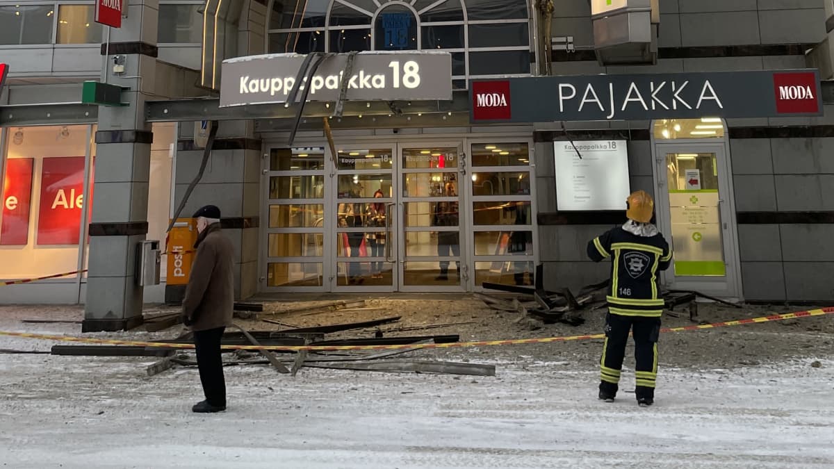 Ohikulkija ja pelastuslaitoksen työntekijä Kauppapaikka 18:n edessä romahdusonnettomuuden jälkeen.