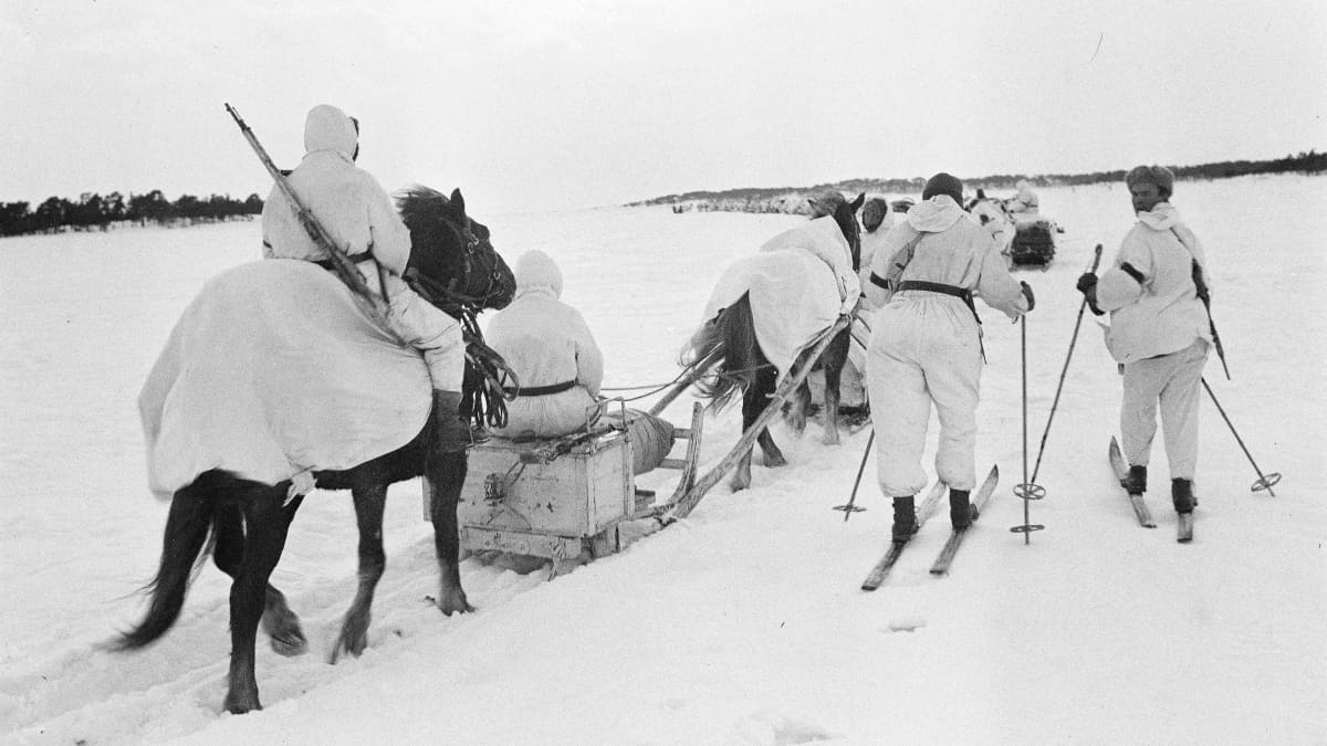 Valkopukuisia suomalaissotilaita meren jäällä. Hiihtävät ja kulkevat hevosen vetämällä reellä.