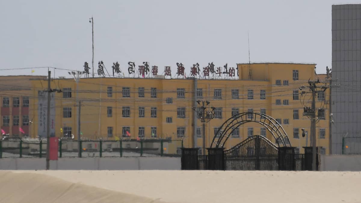 Kiinan lippuja suljetun portin ja korkealla aidalla aidatun alueen edustulla.
