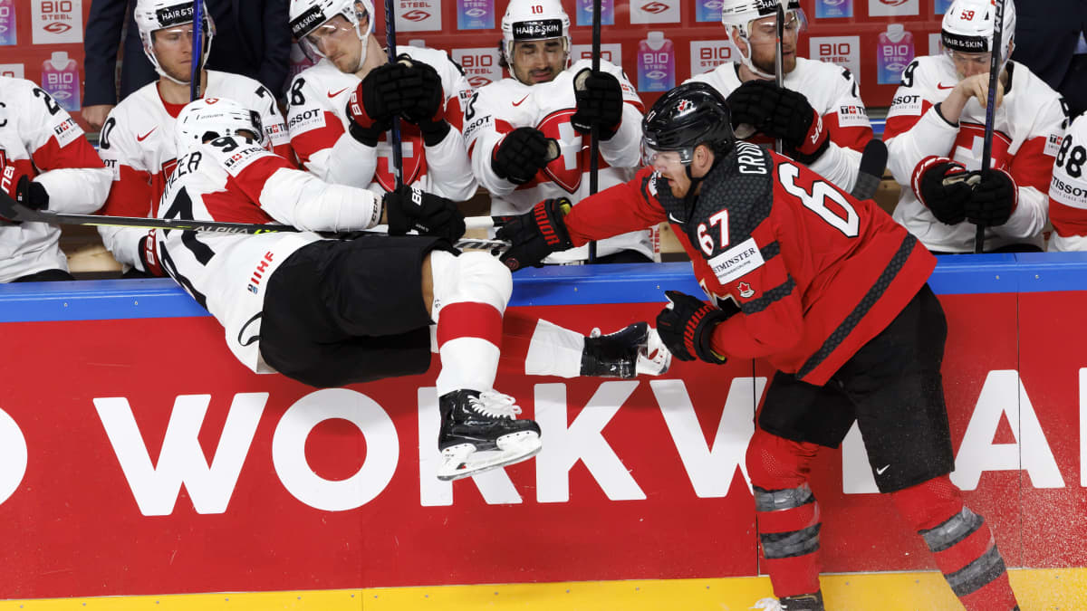 Kanadan Lawson Crouse jyrää Sveitsin Jonas Siegenthalerin jääkiekon MM-ottelussa Riiassa 2023.
