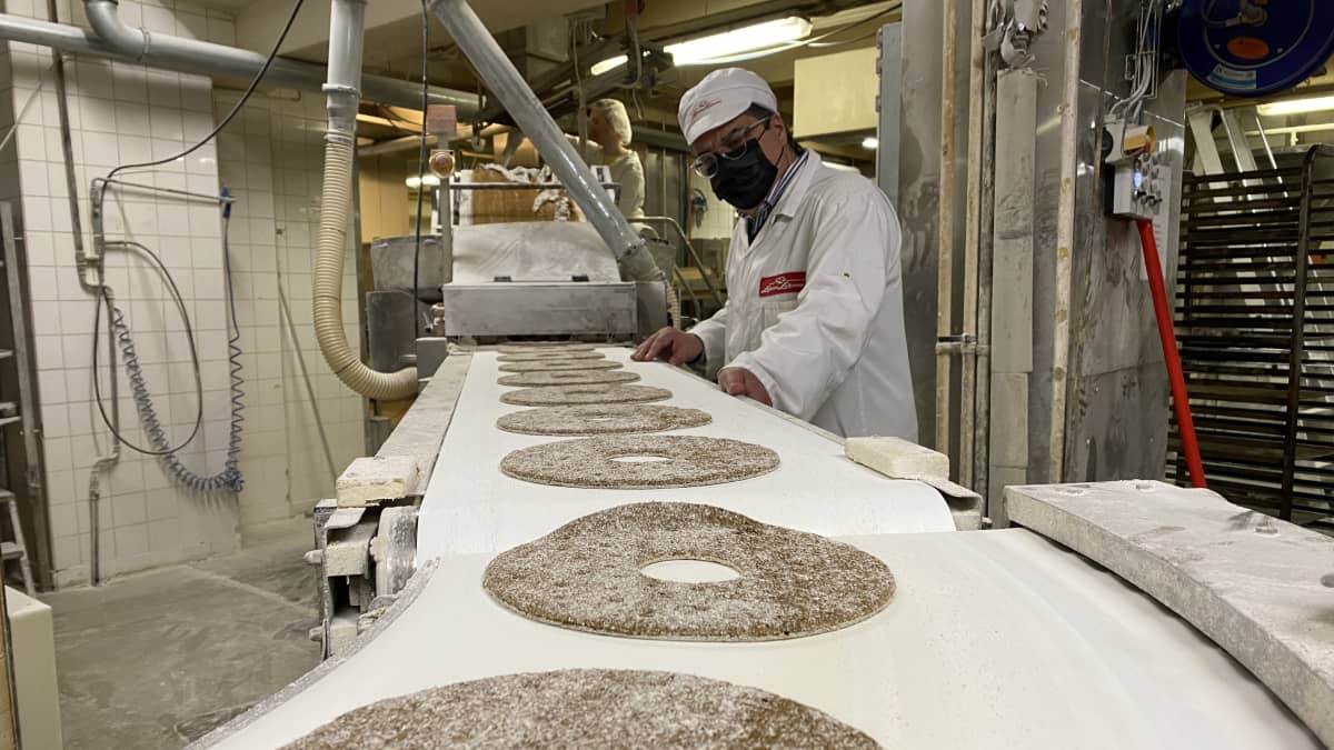 Valkoisiin pukeutunut Leivon leipomon toimitusjohtaja Harri jaakkola seuraa raakojen ruisleipien kulkua hihnalla. 