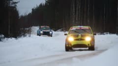 Kaksi ralliautoa ajaa talvisella tiellä peräkkäin.