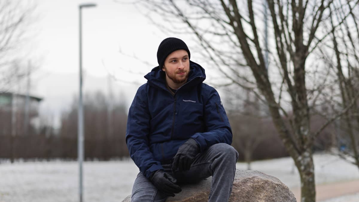 Juho Mettovaara istuu isolla kivellä Oulun lyseon pihamaalla. Sää on pilvinen.