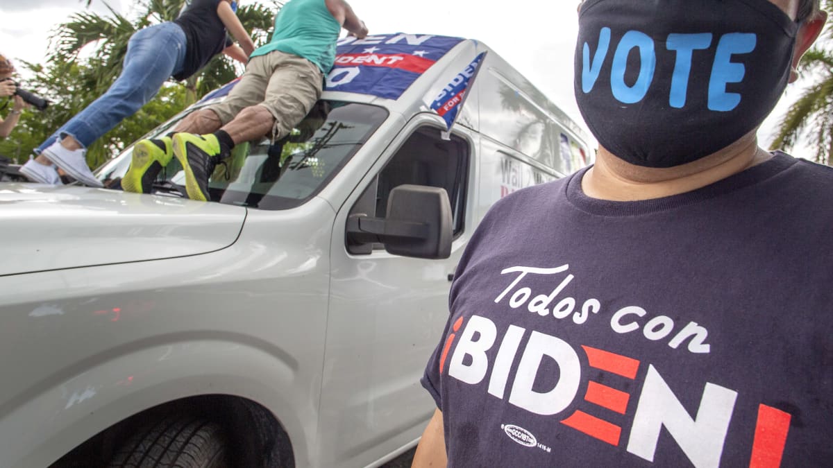 Joe Bidenia kannattavia latinoita Miamissa. Etualalla olevalla naisella lukee paidassa espanjaksi Todos con Biden! Naisen kasvomaskissa lukee englanniksi Vote.