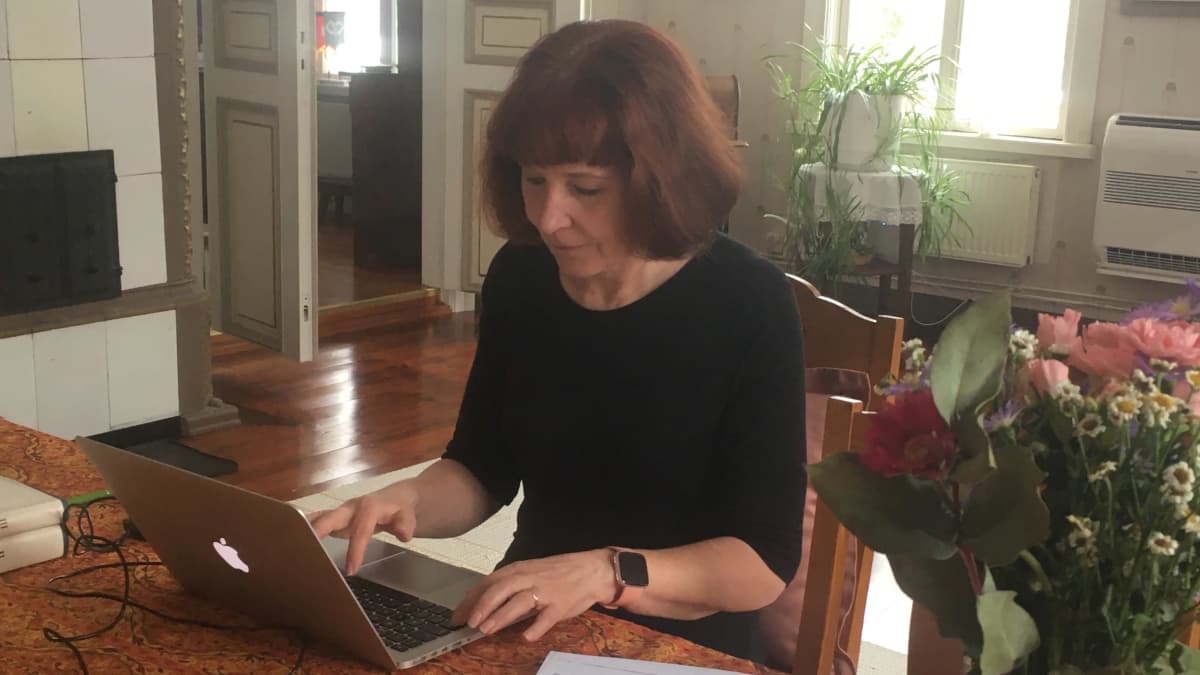 nainen kirjoittaa tietokoneella pöydän ääressä