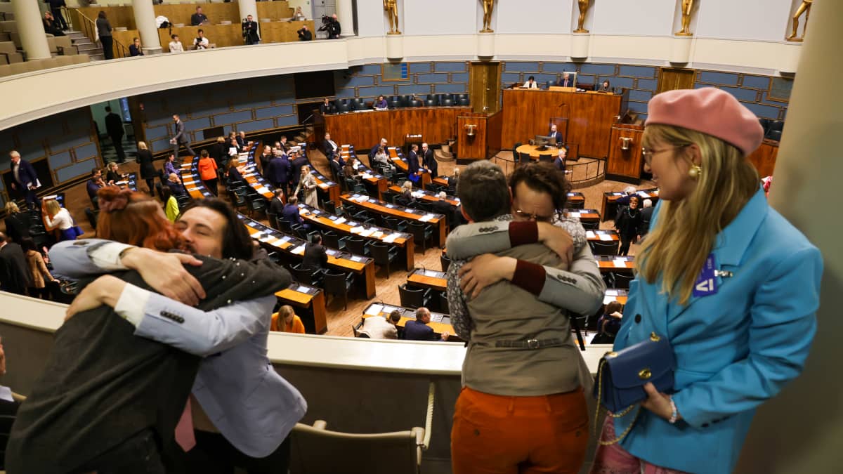 Transhenkilöitä halaamassa  eduskunnan istuntosalin yleisölehterillä.