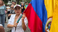 Nainen pitää Kolumbian lippua mielenosoituksessa.