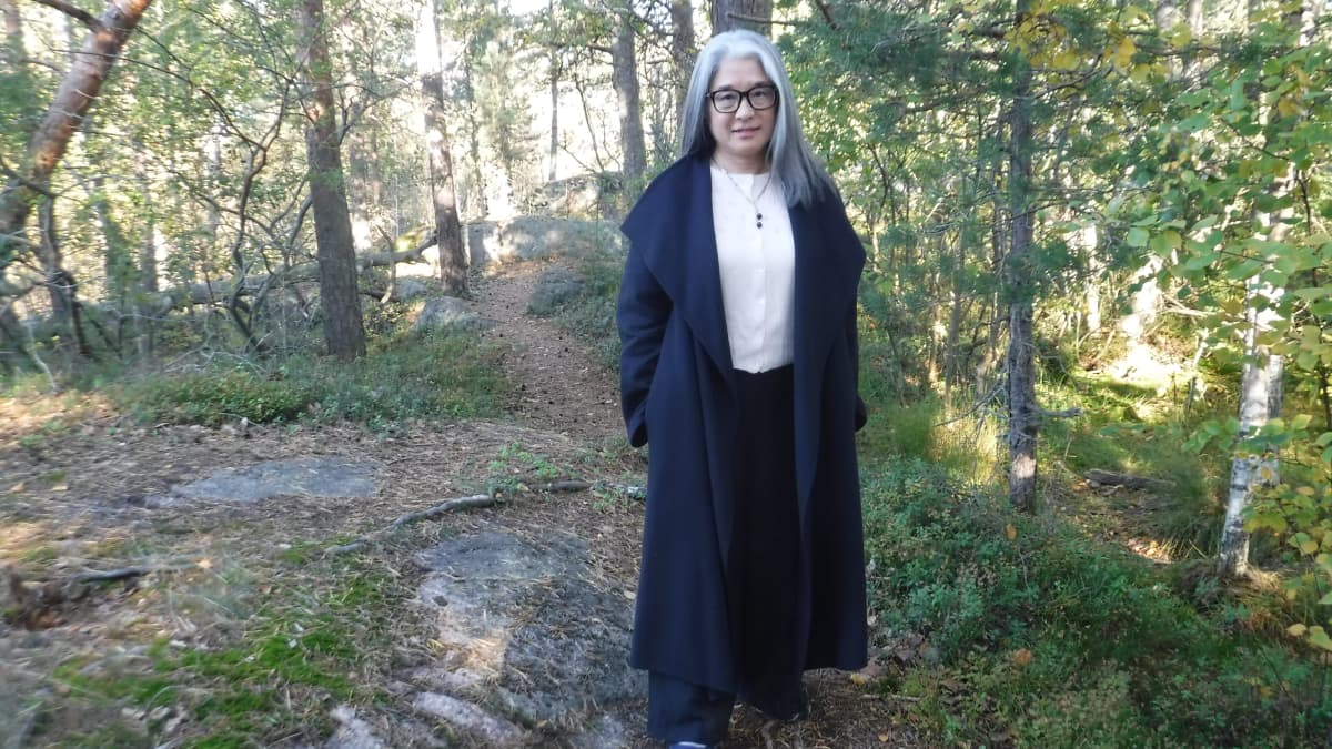 Nainen seisoo syksyisessä metsässä