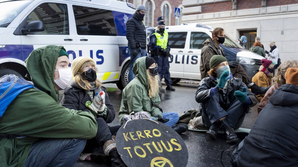 Elokapina mielenosoittajat istuvat kadulla.