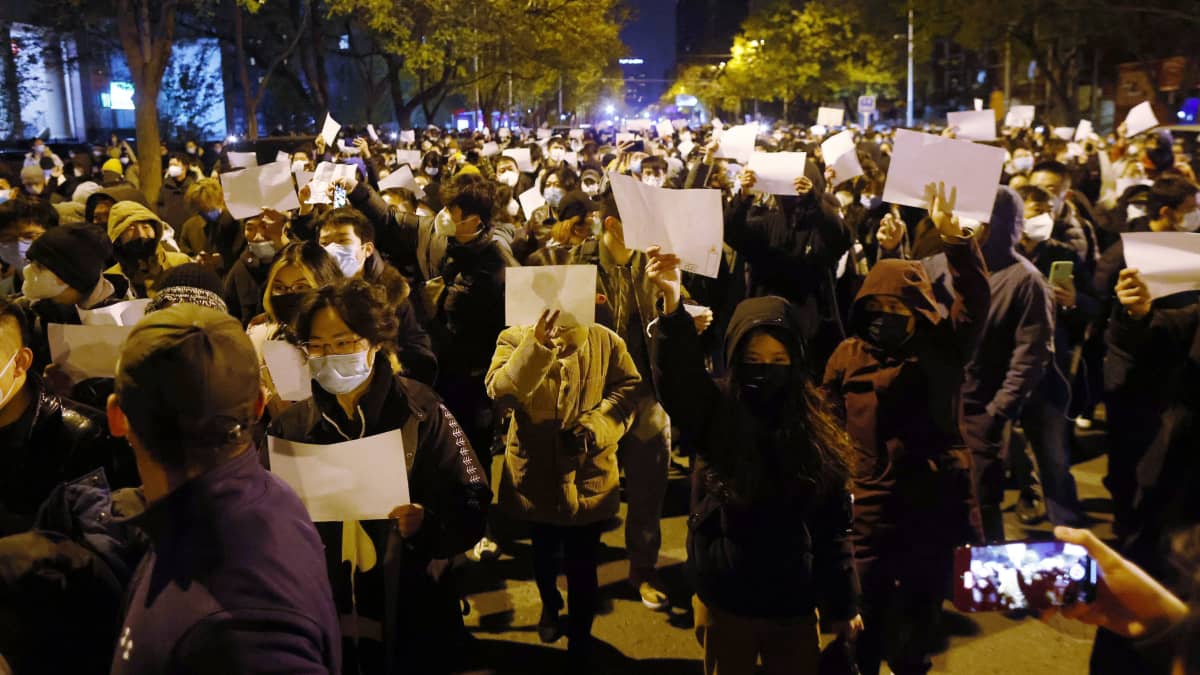 På bilden ses demonstranter hålla vita blanka papper under en protest i Peking mot Kinas covidpolicy.