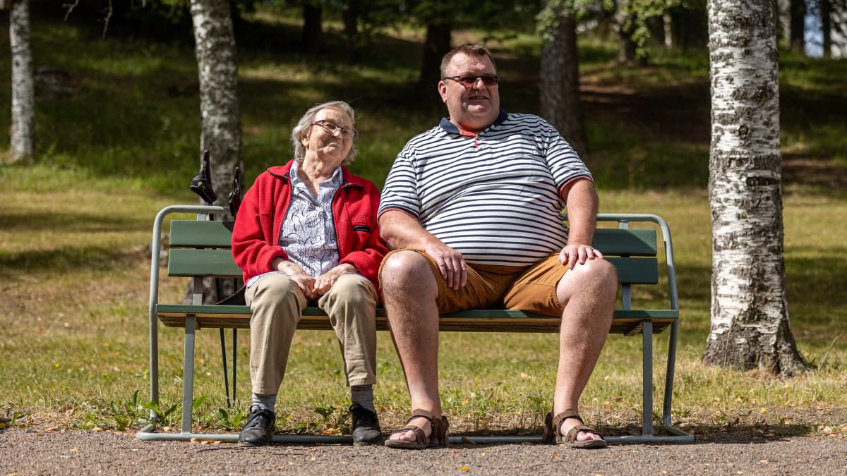 Markku Kostiainen istuu puistonpenkillä iäkkään äitinsä Raili Kostiaisen kanssa.