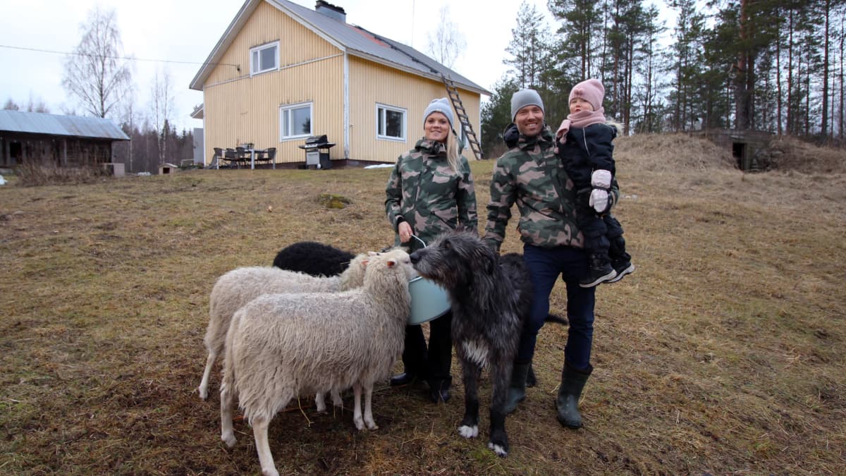 Jalkasten perhe lampaiden ympäröimänä talonsa edessä.