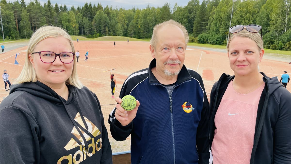 Puulaakipesäpalloilijat Eeva Korhonen Anu Hurtig ja Arto Köngäs seisovat tyytyväisenä Korkalovaaran pesäpallostadionilla.