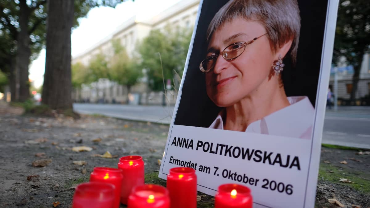 Anna Politkovskajan kuva ja punaisia muistokynttilöitä maassa.