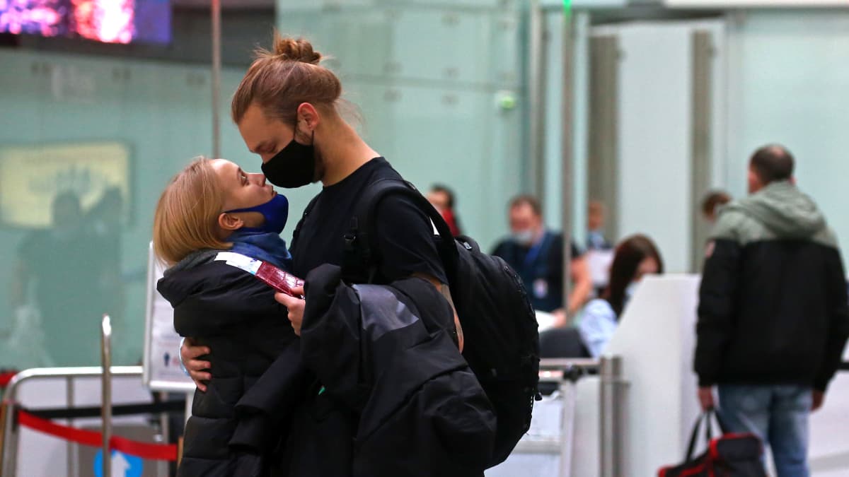 Mies ja nainen halaavat lentoasemalla.