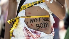 Mielenosoittajan vatsassa kirjoitus: "Not Your Body".