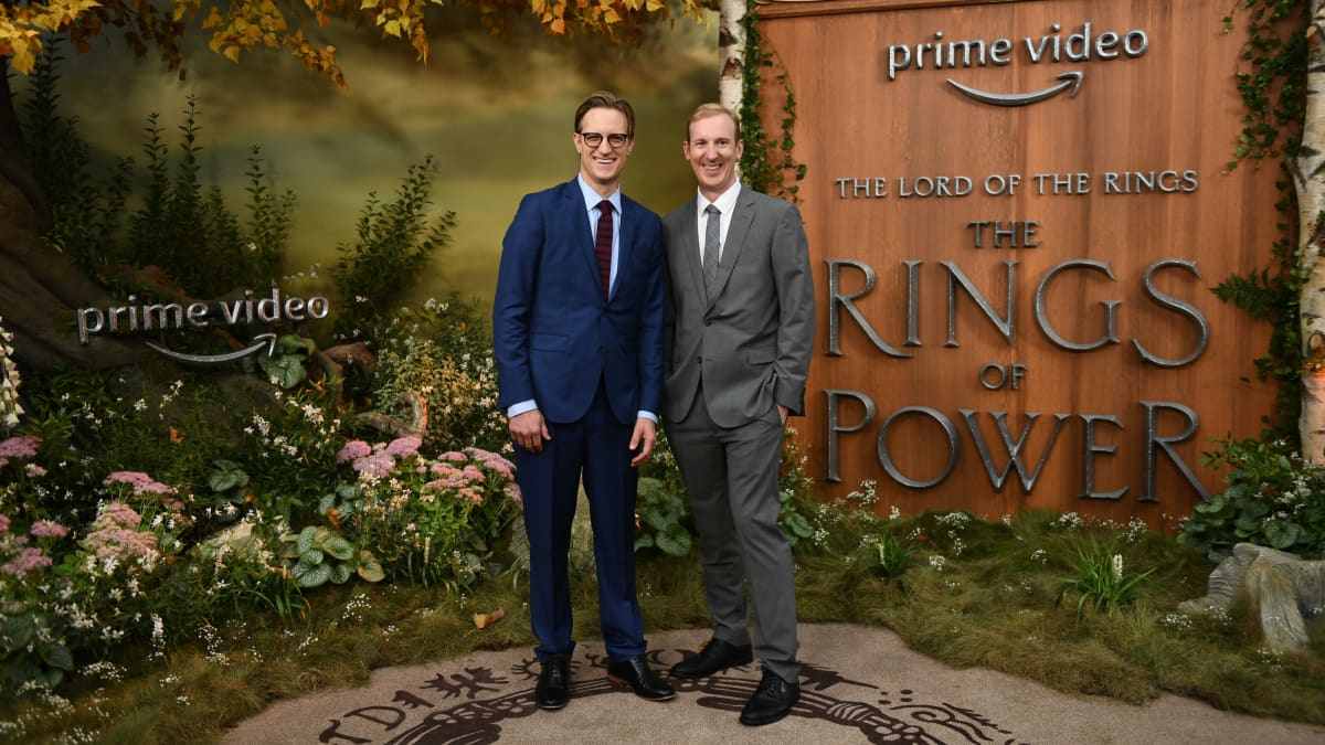 Kaksi valkoista miestä puvuissa lavasteessa, jossa lukee Prime Video ja The Rings of Power.
