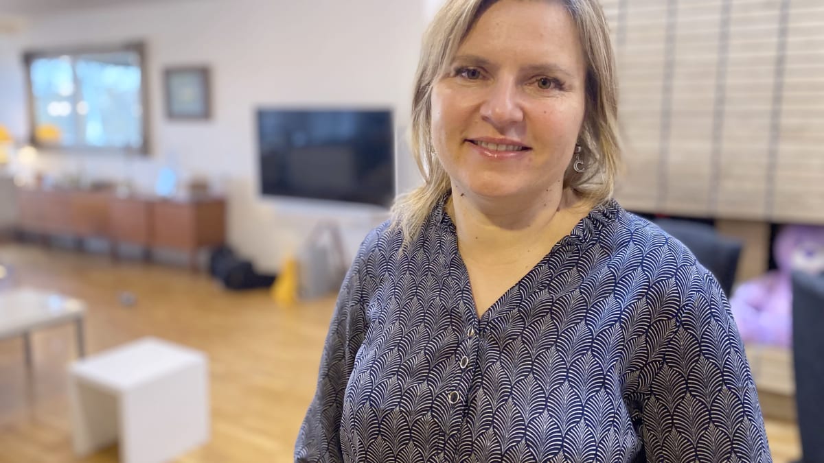 Yrittäjä Riikka-Maria Lemminki seisoo kotonaan olohuoneessa ja katsoo kameraan.
