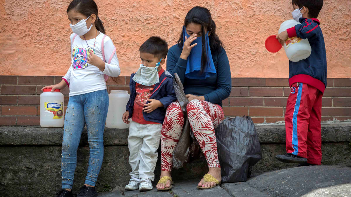 Vesipula vaikeuttaa koronaviruksen torjuntaa. Äiti jonotti vettä Caracasissa lastensa kanssa viime viikolla.