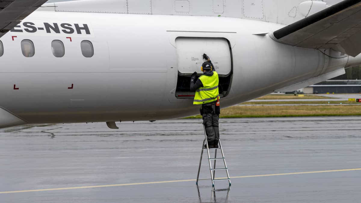 Kenttähenkilökunta avaa matkustajakoneen rahtiluukkua lennon jälkeen