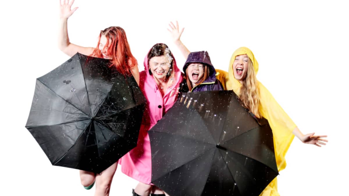 Kuvassa neljä naista seisoo sateenvarjon kanssa.