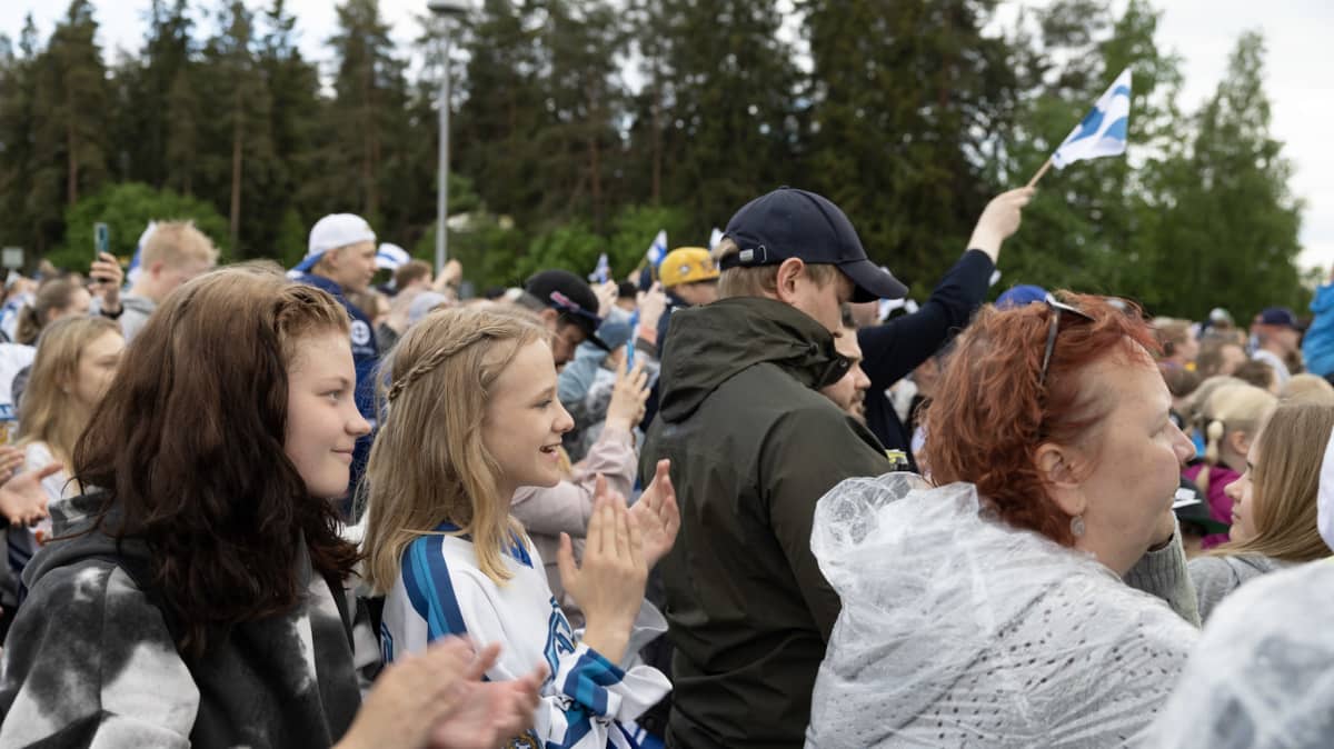 Ihmisiä taputtamassa hymyillen kultajuhlayleisössä.