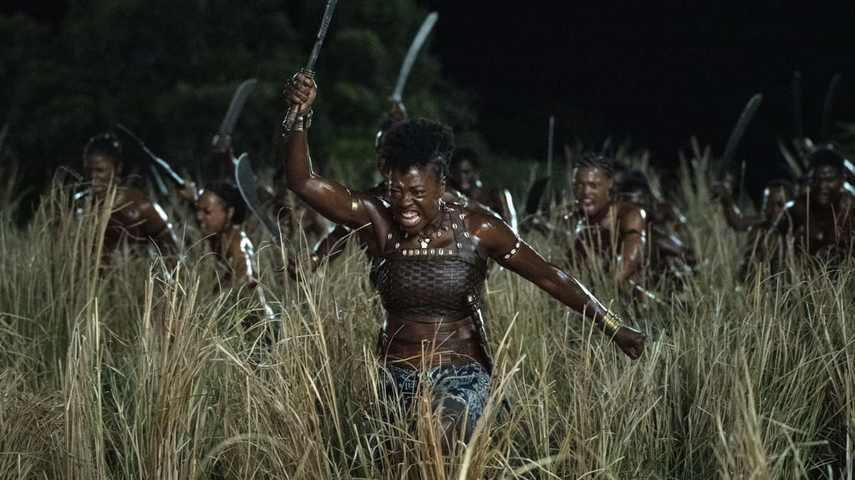 Naisjoukko juoksee pimeässä pellolla miekat pystyssä.