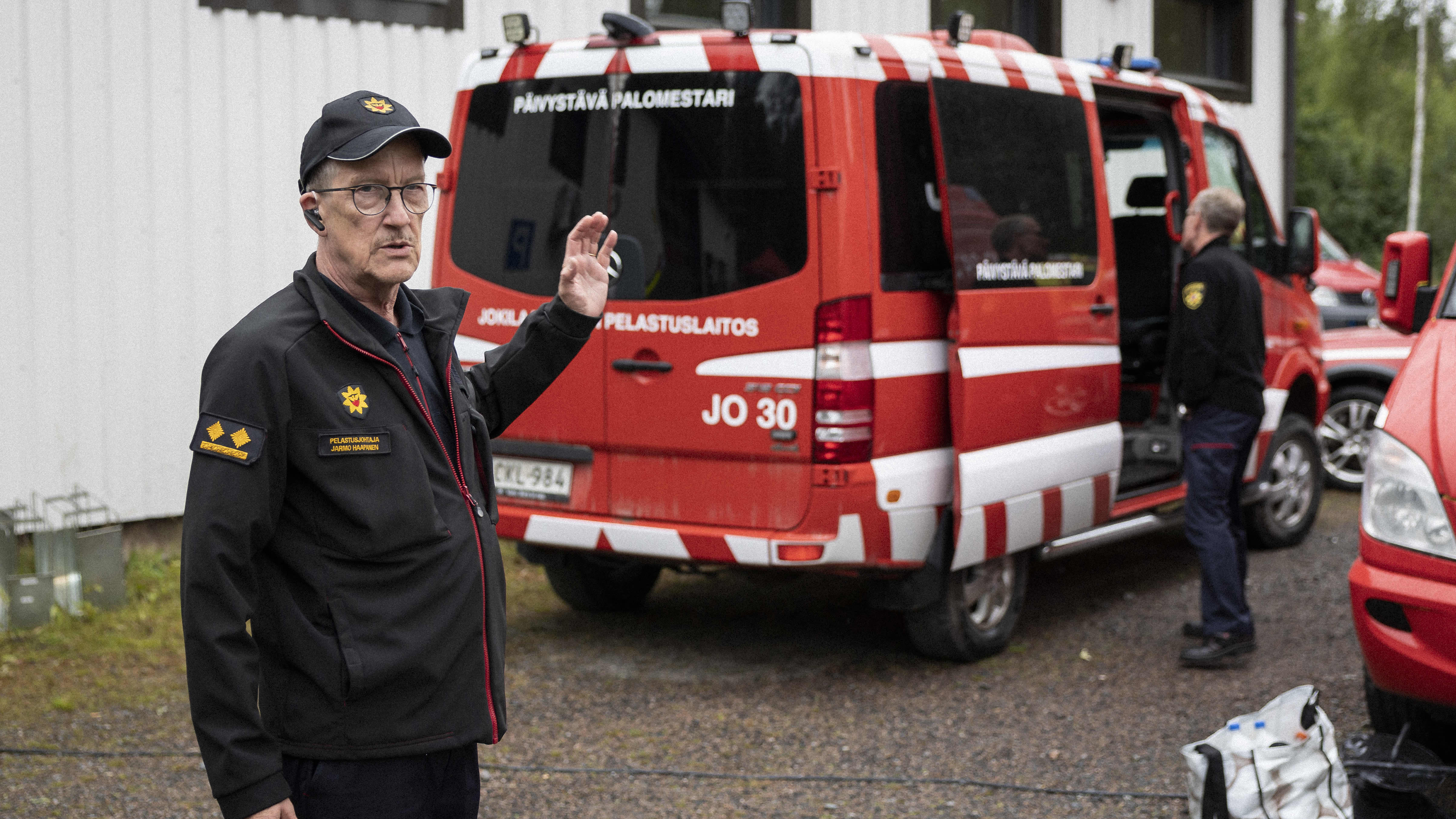 Pelastusjohtaja Jarmo Haapanen taustallaan päivystävän palomestarin auto. 