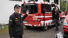 Pelastusjohtaja Jarmo Haapanen taustallaan päivystävän palomestarin auto. 