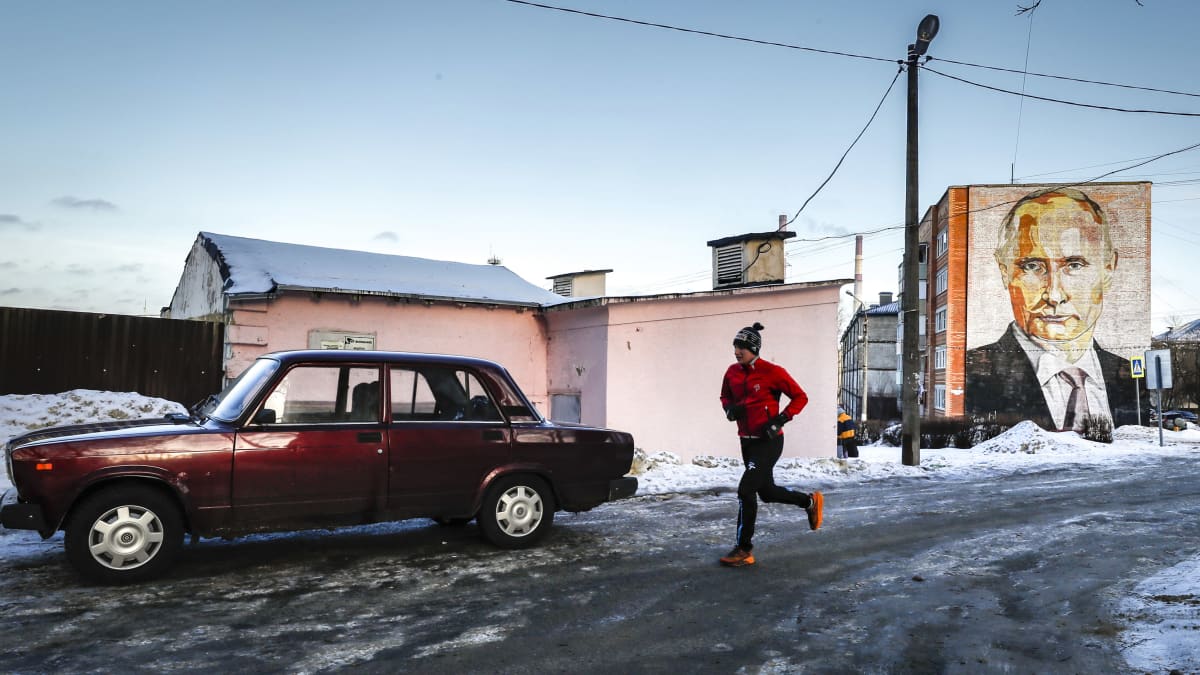 Mies juoksee suuren seinämaalauksen ohi, jossa on Venäjän presidentti Vladimir Putin, Kashirassa Moskovan alueella Venäjällä 12.01.2023.