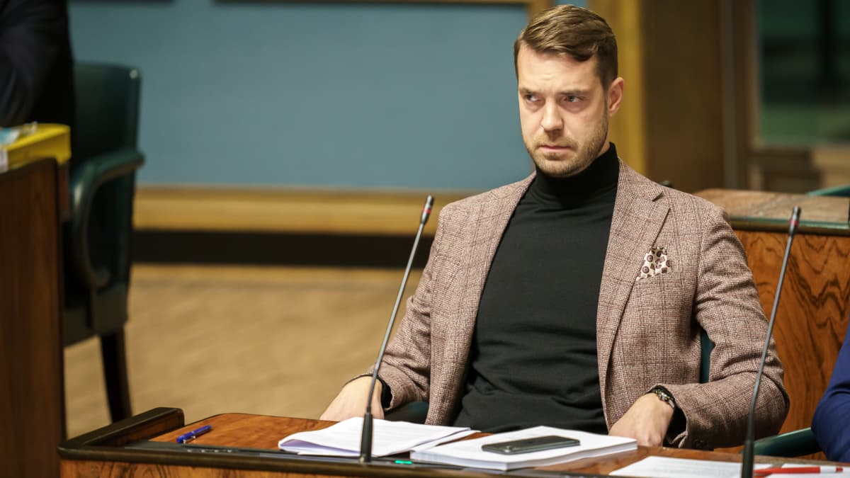 Keskustan kansanedustaja Jouni Ovaska istumassa omalla paikallaan eduskunnan istuntosalissa.