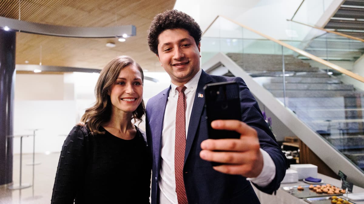 Marin poseeraa yhteiskuvassa ulkomaisen vieraan kanssa.