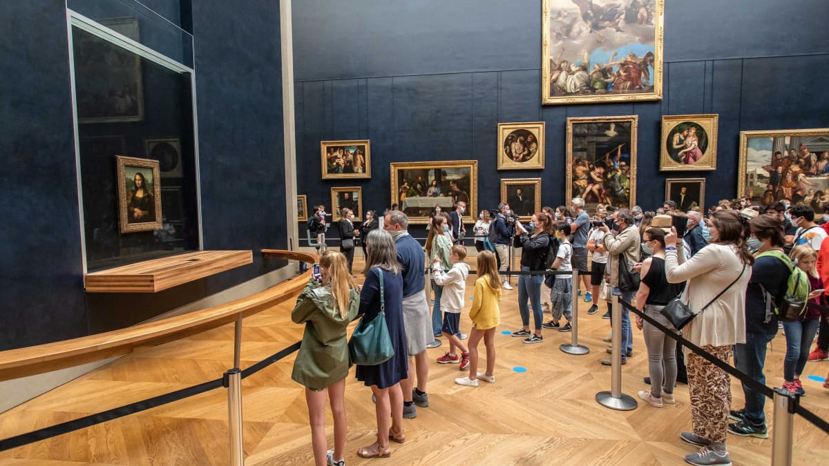 Ihmisia kuvaamassa Mona Lisaa. Lattiassa on sinisiä merkkejä ja kulkuväylä on osoitettu nauhoin.