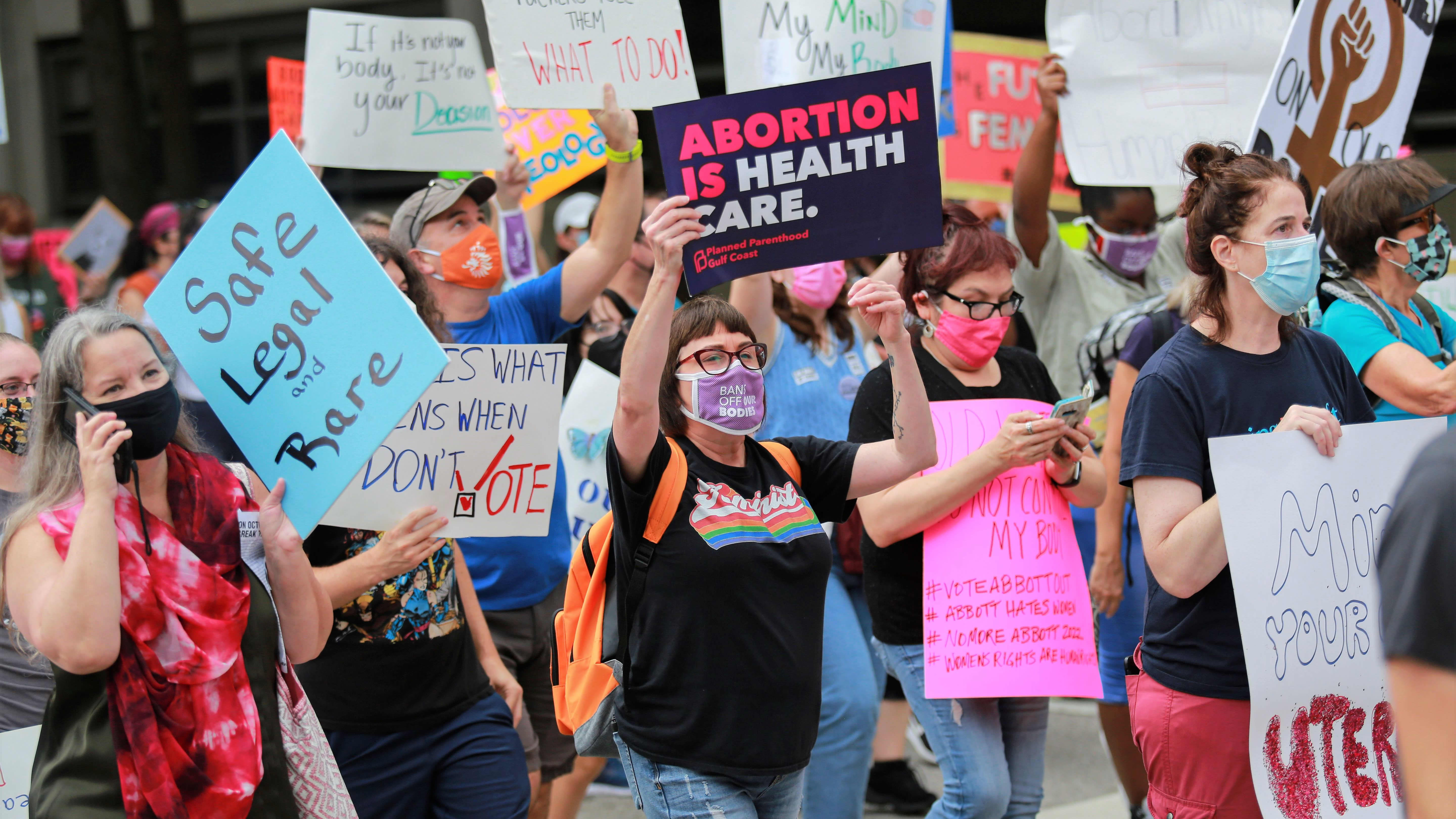 Joukko naisia kulkee plakaattien kanssa. Keskellä kuvaa nainen pitelee kylttiä, jossa lukee englanniksi: "Abortti on terveydenhuoltoa."