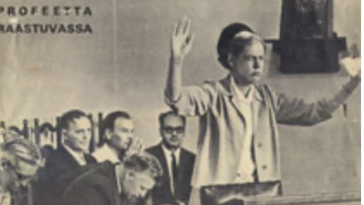 Nainen seisoo oikeussalissa kädet pystyssä.