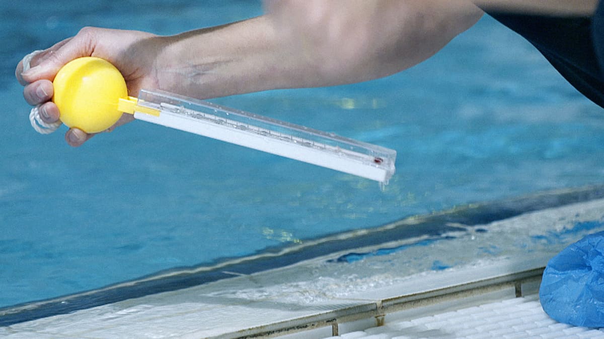 MOT:n toimittaja Kirsi Skön mittaa Janakkalan uimahallin veden lämpötilaa.