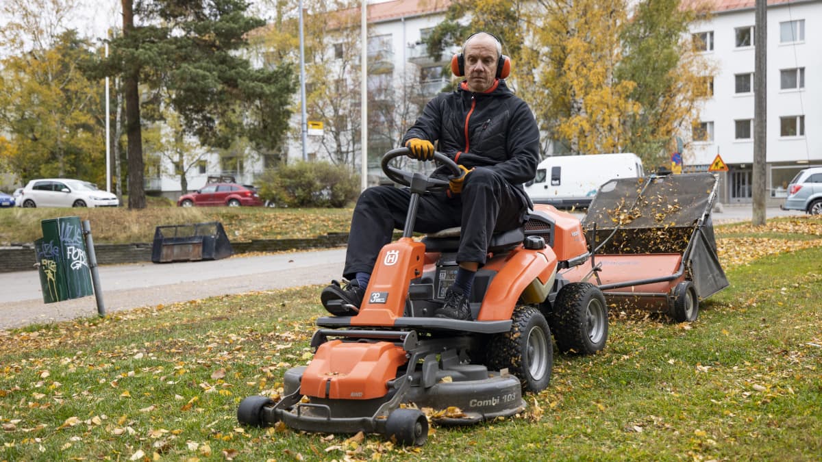 Talonmies Marek Laht kerää lehtiä koneellisesti taloyhtiön pihalla.