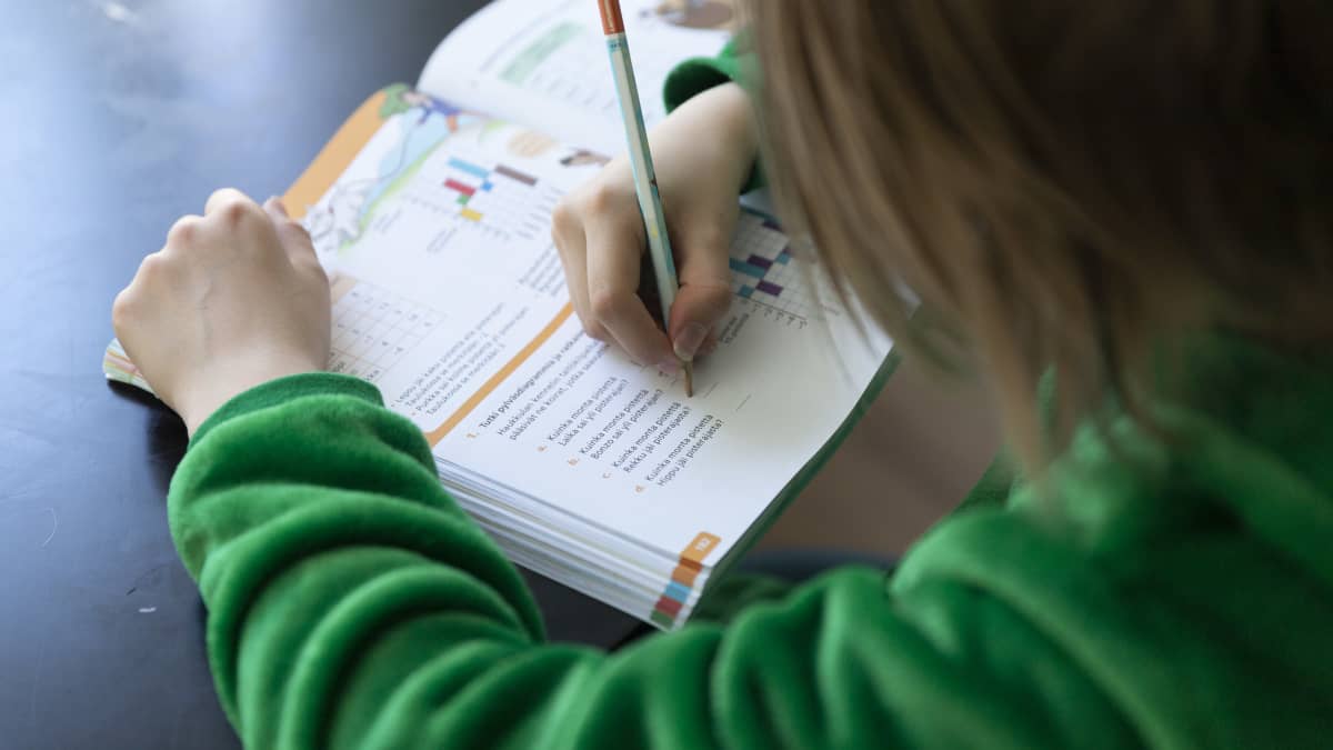 Lapsi tekee matematiikan tehtäviä kirjaan kotona.