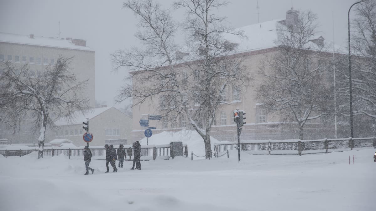 Lumipyry Kouvolan keskusta-alueella ja liikennevaloissa käveleviä henkilöitä.