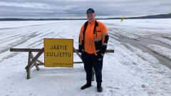 Viitasaarella Kymönkosken jäätietä ylläpitänyt Joni Nurmiranta jään sulusta kertovan kyltin vieressä.