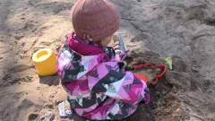 2-vuotias lapsi leikkii hiekkalaatikolla.