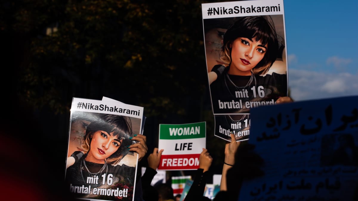 Mielenosoittajat pitelevät kylttejä, joissa on Nika Shakaramin kuva sekä kylttiä, jossa lukee englanniksi "nainen, elämä, vapaus".
