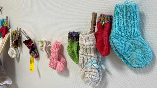 Tiny baby socks on a string decorate a wall.