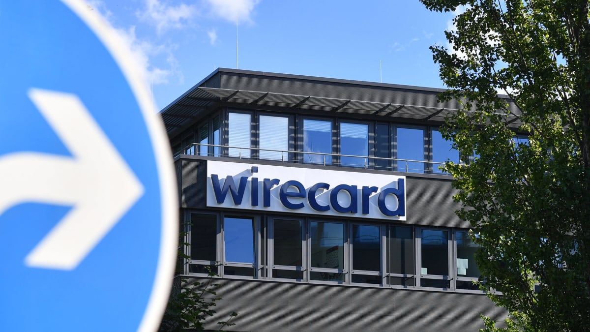 Wirecard-yhtiön nimikyltti rakennuksen seinässä. Etualalla liikennemerkki.